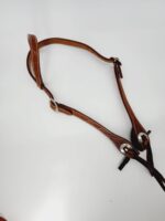 A Cowpuncher Sliding One Ear Headstall With Tooling on a white background. The belt style headstall features metal rings and buckles for adjustment, displaying craftsmanship in its design.