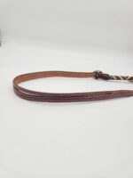 A brown leather belt with white stitching along the edges is displayed on a plain white background. The belt has a multicolored woven section near the buckle end, adding a touch of vibrancy to the classic design.