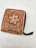 A small, brown leather wallet featuring intricate floral and leaf engravings on the front. The wallet is zippered, with a leather pull tab attached to the zipper. It is displayed on a plain white background.