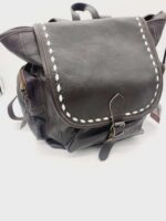 A dark brown leather backpack with adjustable shoulder straps and a flap secured by a buckle. The flap features white stitching along the edges. The bag has a front pocket with a snap closure and side pockets with zippers. It is placed on a white background.