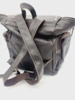 A dark brown leather backpack with adjustable straps laying crisscrossed on a white surface. The backpack features multiple pockets and a top flap closure. The leather has a textured appearance with visible stitching along the edges.