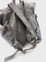 A close-up of a black leather backpack with brown stitching. The backpack has multiple pockets and adjustable shoulder straps. The material appears rugged and durable, suitable for daily use. The photo is taken against a white background.