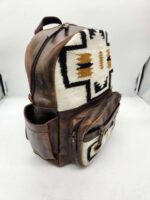 A stylish backpack with a brown leather exterior and a fabric front panel featuring a geometric Aztec pattern in black, white, and brown. The backpack has multiple zippered compartments and is displayed against a plain white background.