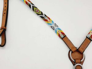 A close-up view of a horse breast collar featuring colorful beadwork on the straps. The bead design includes patterns in red, yellow, blue, black, and white. The leather parts are light brown and attached with metal rings and buckles.