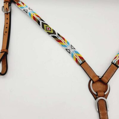 A close-up view of a horse breast collar featuring colorful beadwork on the straps. The bead design includes patterns in red, yellow, blue, black, and white. The leather parts are light brown and attached with metal rings and buckles.