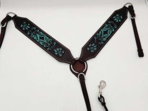 A leather horse breast collar with intricate turquoise embroidery. The design features floral patterns on dark brown leather. The collar has metal rings and clips for attachment and is photographed on a plain white background.