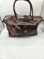 A rustic brown **Leather Duffel Bag- City Square** with sturdy double handles and a zippered top. The bag features a front buckle pocket, a small side loop, and an additional shoe pocket. The leather has a worn, vintage look, giving it character and charm. The background is plain white.