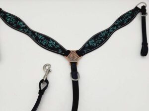 A black horse breast collar with intricate blue and green embroidery and a silver-tone center decoration is laid out flat on a white surface. It features silver rings and adjustable straps with clips.