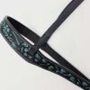 Black leather belt with intricate blue and light blue embroidered designs. The belt features neatly stitched borders and appears to have a buckle for fastening. It is displayed on a white background.