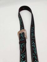 A brown leather belt with intricate turquoise and black floral embroidery along its length. The belt has a decorative, gold-toned metal buckle with engraved patterns. The background is plain white.