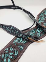 Close-up image of a brown leather breast collar with intricate turquoise floral patterns. The leather is intricately tooled with flower designs and features silver buckles and tan leather straps.