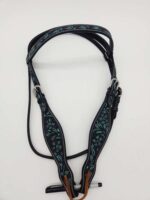 A black leather horse bridle adorned with intricate turquoise embroidery and silver-toned buckles lies on a white background. The detailed floral patterns add decorative elegance to the sturdy straps. A pen is placed at the bottom for scale.