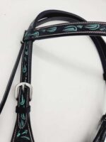 A close-up of a black leather bridle with intricate turquoise stitching and designs. The bridle features a silver buckle and is placed on a plain white background.