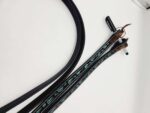 A close-up photo shows turquoise and black beaded reins laying on a white surface. The reins are made of black leather with intricate beading and have attached silver hardware at one end. There is also a black strap visible to the left of the reins.