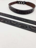 A black leather belt and strap featuring intricate sunflower engravings are laid out on a white background. The belt has a buckle with silver studs, while the strap showcases the floral design prominently.