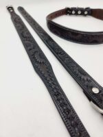 A detailed image of three leather straps with intricate floral patterns embossed on them. There are two narrow black straps placed parallel to each other and a wider, dark brown belt-like strap with metallic buckles and studs. The background is white.