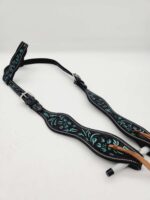 A black leather horse bridle featuring intricate turquoise floral designs is laid out against a plain white background. The bridle has adjustable silver buckles and reinforced stitching along the edges.