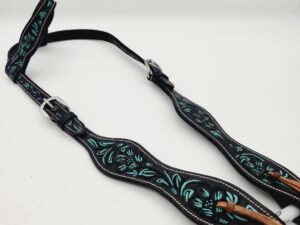 A black leather horse bridle featuring intricate turquoise floral designs is laid out against a plain white background. The bridle has adjustable silver buckles and reinforced stitching along the edges.