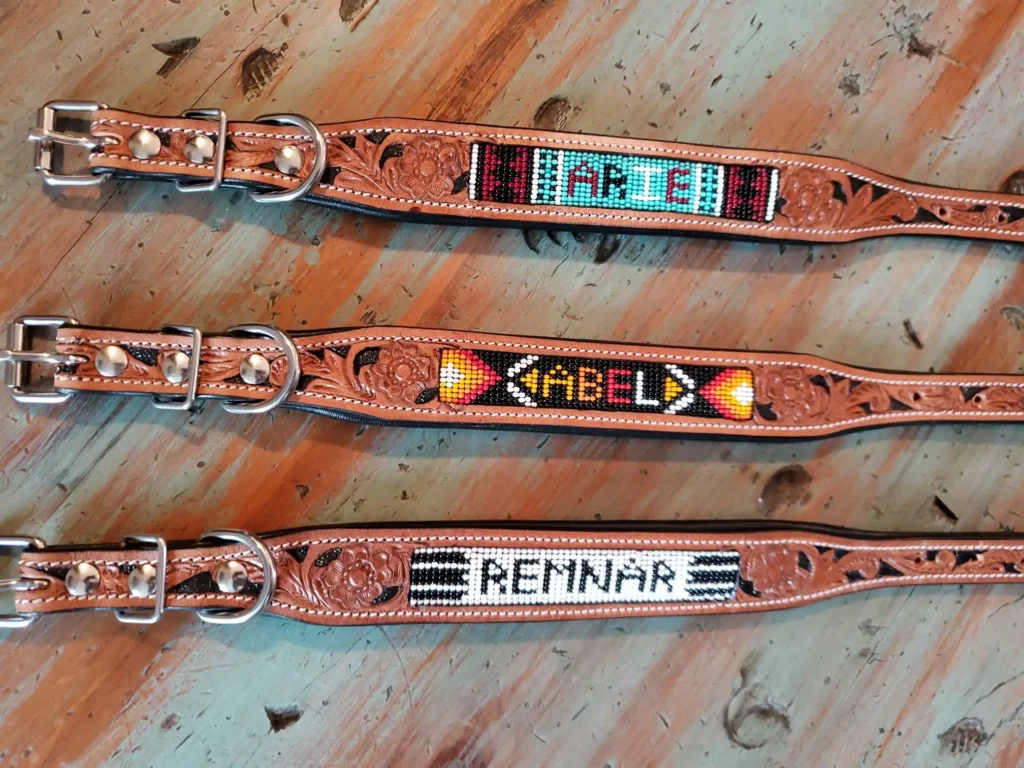 Three intricately designed leather belts, each featuring colorful beaded names: "ARCH" on the first belt with white, blue, and black beads; "ABEL" on the second belt with orange and yellow beads; and "REMNAR" on the third belt with black and white beads.