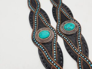 Two "Leather Dog Collar- Blue Earth Gemstone Dog Collars" with intricate turquoise and brown bead designs resemble elegant dog collars. Each collar features a large turquoise stone in the center, framed by ornate metallic decorations. The collars have a braided texture and are symmetrically laid out side by side.