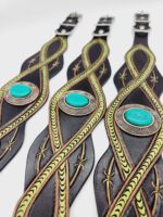 Close-up of three decorative leather belts featuring intricate green braided designs and large turquoise oval stones set in ornate metal settings. The belts are displayed in a row, highlighting their detailed craftsmanship and bright color contrast.