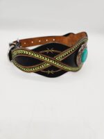 A black leather dog collar with intricate green leather designs and a turquoise stone centerpiece. The collar has a metal buckle and stitching details on the edges. The background is plain white.