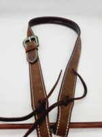 A brown leather belt with a silver buckle is laid out on a white background. The belt has white stitching along the edges and leather laces attached near the buckle for additional fastening options.