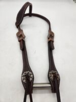 A leather headstall with intricate silver decorations and two buckles. The headstall features detailed stitching and metal accents. The background is plain white.