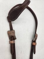 A brown leather horse bridle with decorative metal buckles and intricate stitching is laid out against a white background. The bridle appears worn, indicating regular use.