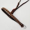 A brown leather belt with white stitching and metal buckle is laid out flat on a white surface. The belt has an intricate loop and knot design near the buckle, adding a decorative touch.