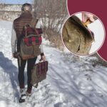 A person with blonde hair, wearing a brown vest, grey sleeves, and black leggings walks on a snowy path. They carry a brown and red plaid backpack and hold a matching bag. An inset shows a close-up of the backpack's waxed canvas material and detail.