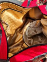 A close-up view of the inside of an open red and tan bag, showing its yellowish-gold interior lining. There are several pockets visible, including a large main compartment and a zippered side pocket. The bag fabric has a soft texture.