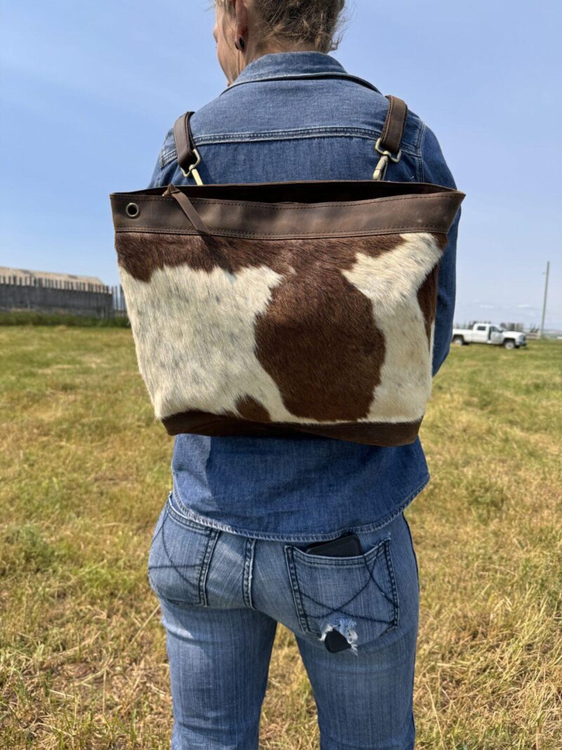brown and white cowhide bag slung over their shoulder. cross body purse backpack hair on cowhide purse